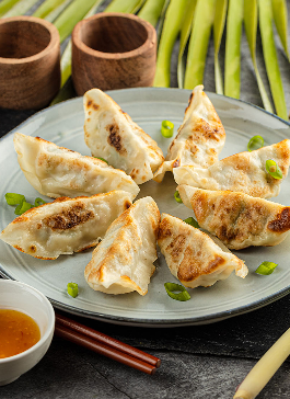 Des gyozas AGIS légèrement dorés présentés dans une assiette et accompagnés d'une sauce