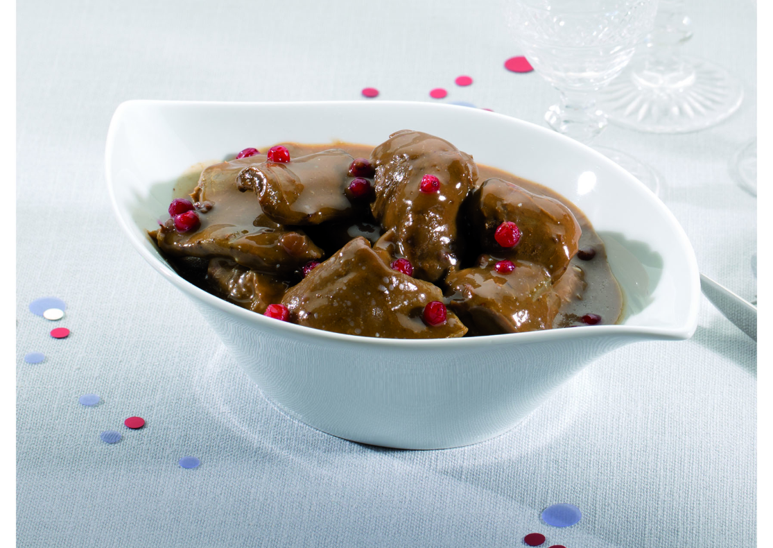 Un sauté de chevreuil accompagné de sa sauce grand veneur avec quelques baies d'airelles sur le dessus du plat.