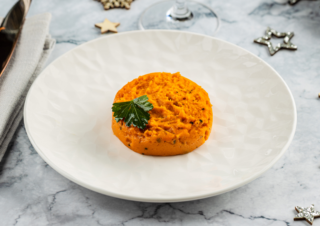 Une timbale de patate douce de couleur orange présentée dans une assiette blanche